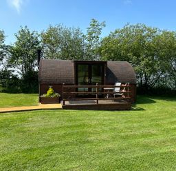 A wooden pod with decking and furniture at Gelert Pod St Asaph