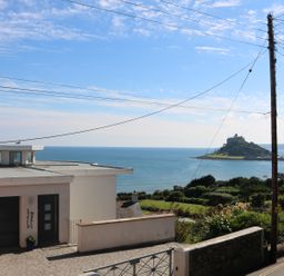 A house near the sea with an island and castle in the background at Ner Sea in Marazion