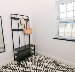 A hallway with a black bench and coat rack a mirror on the wall and a window at The Shell at the Hideaway in Tenby