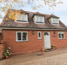 A brick house with three dormer windows and a white door at The Lodge off High Street in Hadleigh