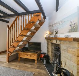 A living room with a staircase and television at The Cottage in Marian-Glas