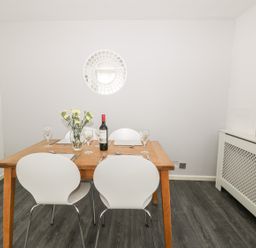 A dining room with a wooden table set with wine glasses flowers and a bottle of wine at 11 Camden Building in Kendal