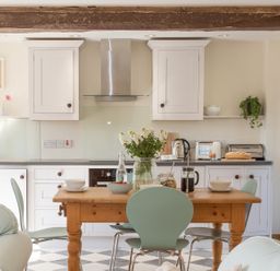 A kitchen with a wooden dining table and green chairs with flowers and breakfast items at Salters Black Dog near Crediton
