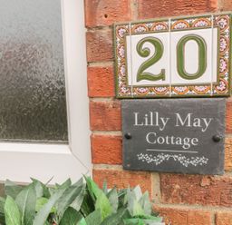 A close up of house number 20 and Lilly May Cottage nameplate on a brick wall