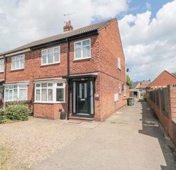 A brick semi detached house with a black front door and gravel driveway at Lilly May Cottage in Flamborough