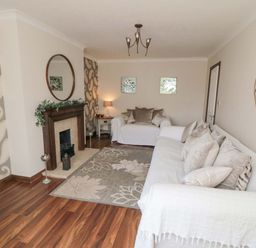A living room with two sofas a fireplace a rug and decorative wall art at Lilly May Cottage in Flamborough