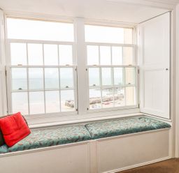 A window seat with cushions and pillows in a room with a view of the sea at Apartment 2 in Tenby