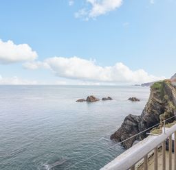 A coastal view with rocks in the sea and a stone staircase on a cliff at Oceans Side in Ilfracombe