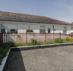 A single story house with a wooden railing and garden in front at Sea Spray in Dinas Dinlle