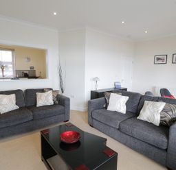 A living room with two gray sofas and a black coffee table with a red bowl at Apartment 3 Marian Y Mor in Pwllheli