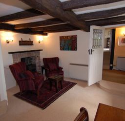A sitting room with two armchairs and a small table on a rug near a fireplace at Appletree Cottage in Higher Brimley near Bovey Tracey