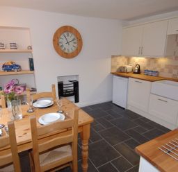 A kitchen with a wooden dining table set for four and white cabinets at Jordan House in Boscastle