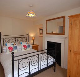 A bedroom with a metal bed frame two wooden bedside tables lamps and a wooden wardrobe at Jordan House in Boscastle