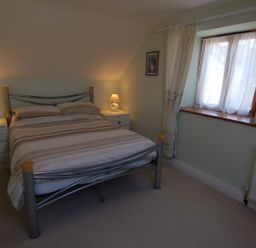 A bedroom with a double bed between two bedside tables with lamps next to a window at The Old Cider Barn in Wookey