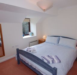 A bedroom with a double bed and two bedside tables with lamps at Pine Cottage in Maenporth