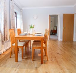 A dining room with a wooden table set for four and wooden chairs at Little Waycroft in Dawlish