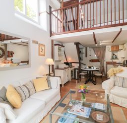 A living room with sofa armchair glass coffee table dining area and wooden beams at The Granary in Edington near Street and Glastonbury