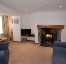 A living room with a fireplace tv table and blue sofas at The Keep Pot in Port Isaac