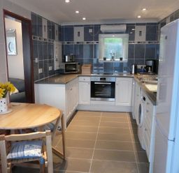 A kitchen with appliances wooden dining table with chairs and flowers at The Keep Pot in Port Isaac