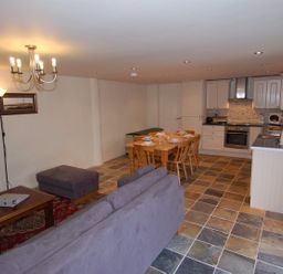 An open living space with a kitchen dining table and sofa at The Barn in Tregoodwell