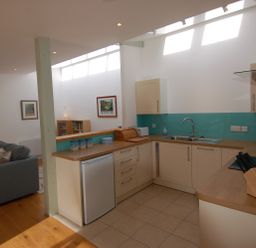 A kitchen with wooden countertops and cream cabinets next to a living area with a sofa at Orchard Retreat in Sidmouth