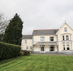 A large two-story house with a lawn and trees at Muriau Park in Caernarfon