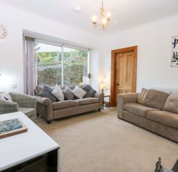 A living room with two sofas and a television at 2 Argoed Llanbedrog