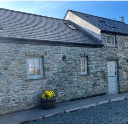 A house exterior with stone walls and a pathway at Storws Tanrallt Llanfachraeth