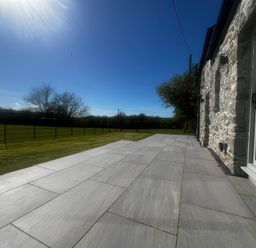 A paved terrace with a grass lawn at Storws Tanrallt in Llanfachraeth