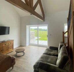 A living room with a sofa and television at Storws Tanrallt in Llanfachraeth