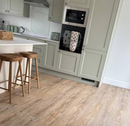 A kitchen with bar stools and cabinets at Storws Tanrallt Llanfachraeth