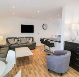 A living room with sofas pillows coffee table bar stools and a chest of drawers at 7 Marina View in Pwllheli