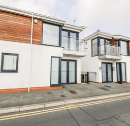 A street view of modern two story buildings with glass balconies and large windows at 7 Marina View in Pwllheli