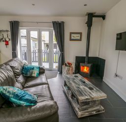 A living room with a sofa and a wood stove at Hafod Wen in Pentraeth