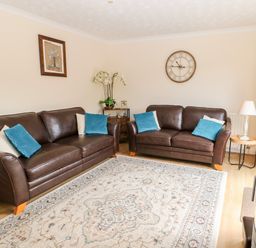 A living room with two brown leather sofas and blue cushions at 14 The Maltings in Rothbury