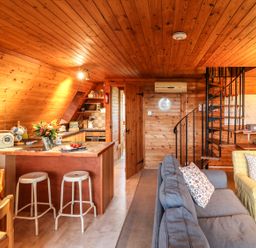 A wooden interior living area with kitchen island stools spiral staircase and seating at Rose Lodge in Milton on Stour