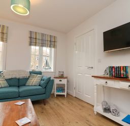 A living room with a teal sofa and a wooden coffee table with coasters at Dotty's Sunshine Cottage in The Bay near Filey
