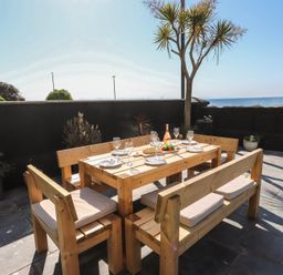 An outdoor dining area with a wooden table and benches at Wavecrest in Pwllheli