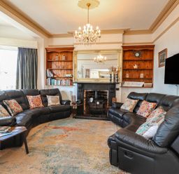 A living room with a sofa and a fireplace at Wavecrest in Pwllheli