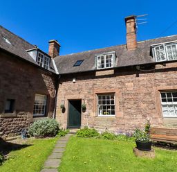 A cottage with a garden and pathway at Gamekeepers Cottage in Chillingham near Chatton