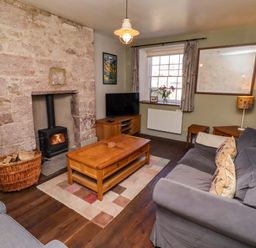 A living room with a fireplace and sofa at Gamekeepers Cottage Chillingham near Chatton