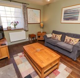 A living room with a sofa and coffee table at Gamekeepers Cottage in Chillingham near Chatton