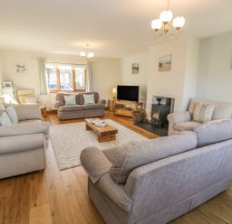 A living room with sofas a TV wood stove and coffee table at Awel Y Llan in Llanfair