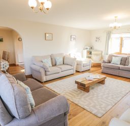 A living room with sofas a wooden coffee table and a dining area at Awel Y Llan in Llanfair