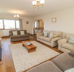 A living room with sofas coffee table and a dining area visible through an archway at Awel Y Llan in Llanfair
