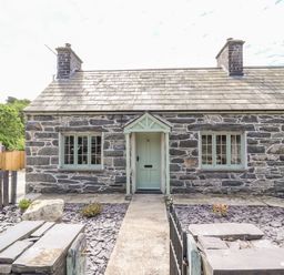Stone cottage exterior with slate roof and green door and windows at Ffrwdd Galed Uchaf in Tregarth