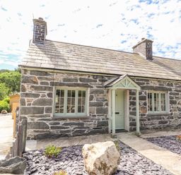A stone cottage with a slate roof and three windows with a small porch at Ffrwdd Galed Uchaf in Tregarth