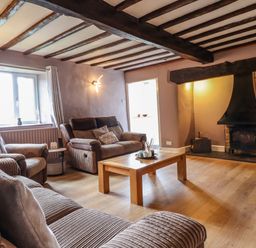 A living room with sofas a wooden coffee table and a fireplace at Rhydygaled in Llanrhaeadr-Ym-Mochnant