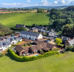 Aerial view of houses with green lawns and fields in the background at The Old Byres in Washford near Watchet