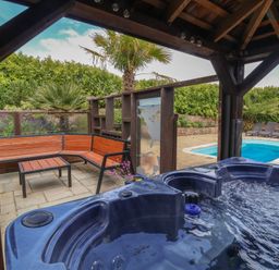A garden with a hot tub and seating area at The Old Byres in Washford near Watchet